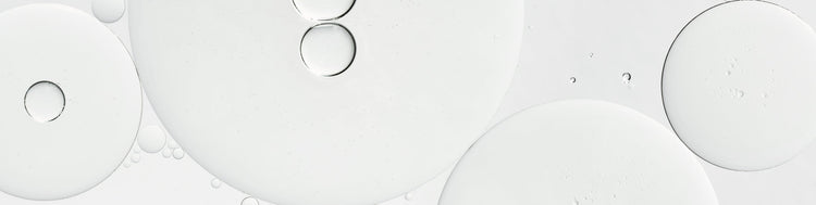 Large and small overlapping translucent white circles with subtle gray outlines and tiny bubbles on a pale background, resembling abstract oil and water droplets.