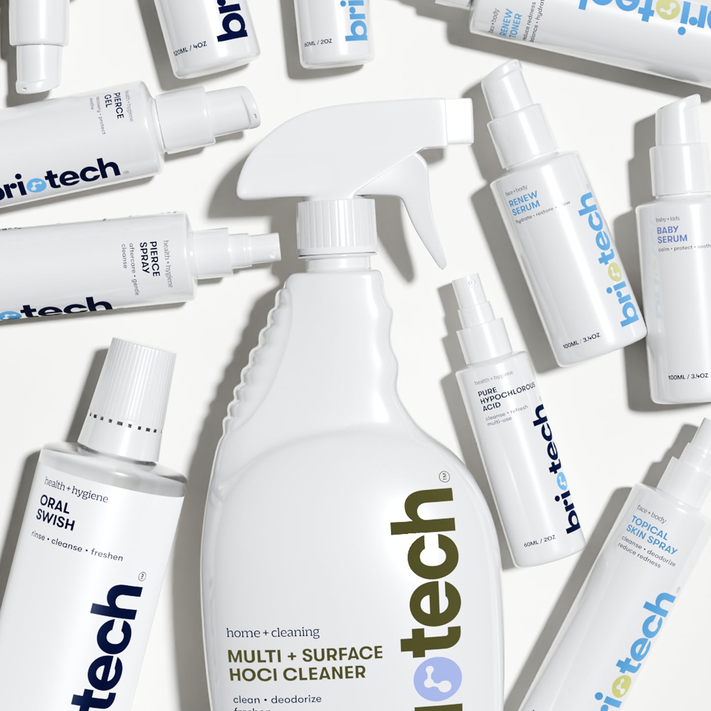 A flat lay of Briotech white bottles, including sprays, pumps, and a large trigger spray labeled Topical Skin Spray—ideal as a soothing skin spray to calm irritation—arranged on a light surface.