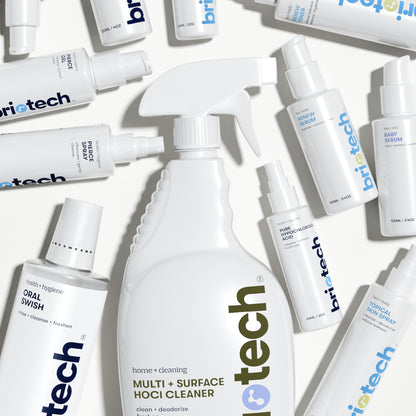 A flat lay of Briotech white bottles, including sprays, pumps, and a large trigger spray labeled Topical Skin Spray—ideal as a soothing skin spray to calm irritation—arranged on a light surface.